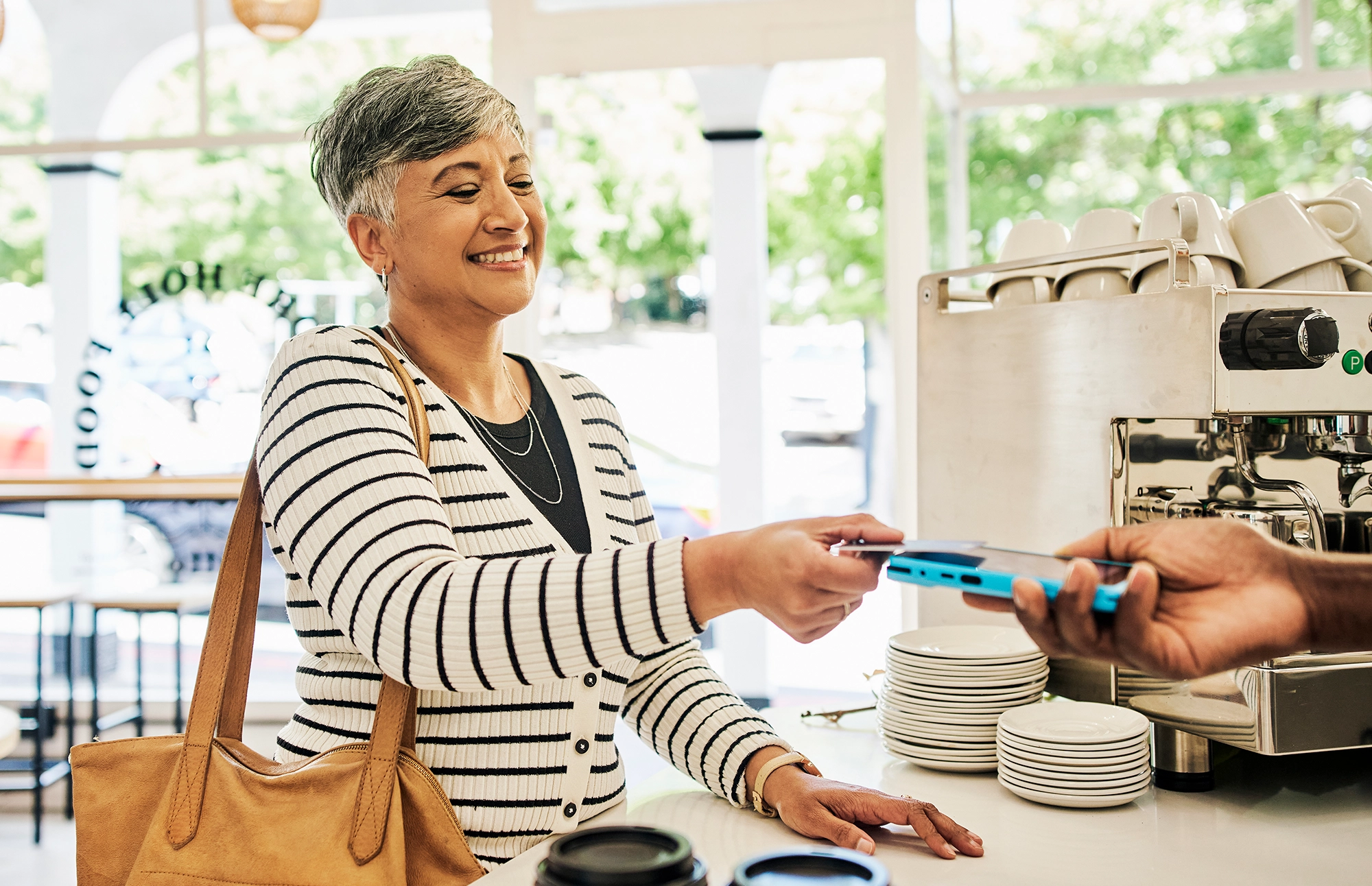 Woman smiles while tapping her card to buy an item at a coffee shop